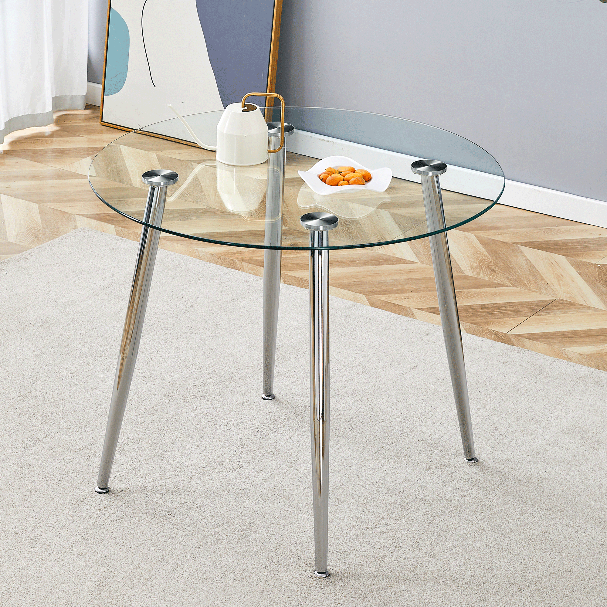 Round glass dining table with tapered silver legs in a styled living room, three-quarter view