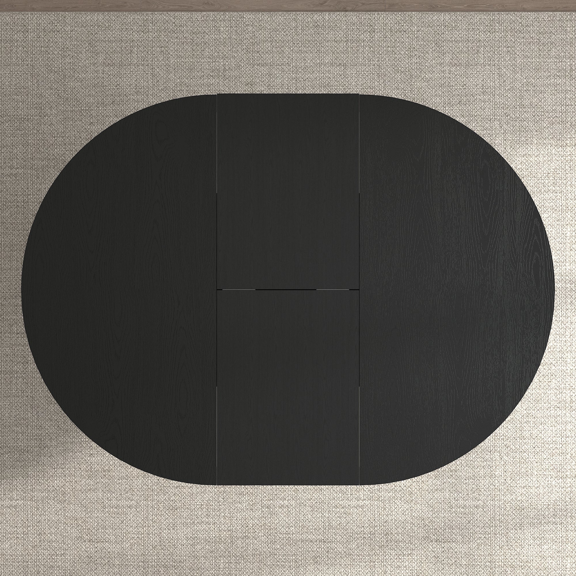 Overhead view of the oval extended black tabletop on a woven rug