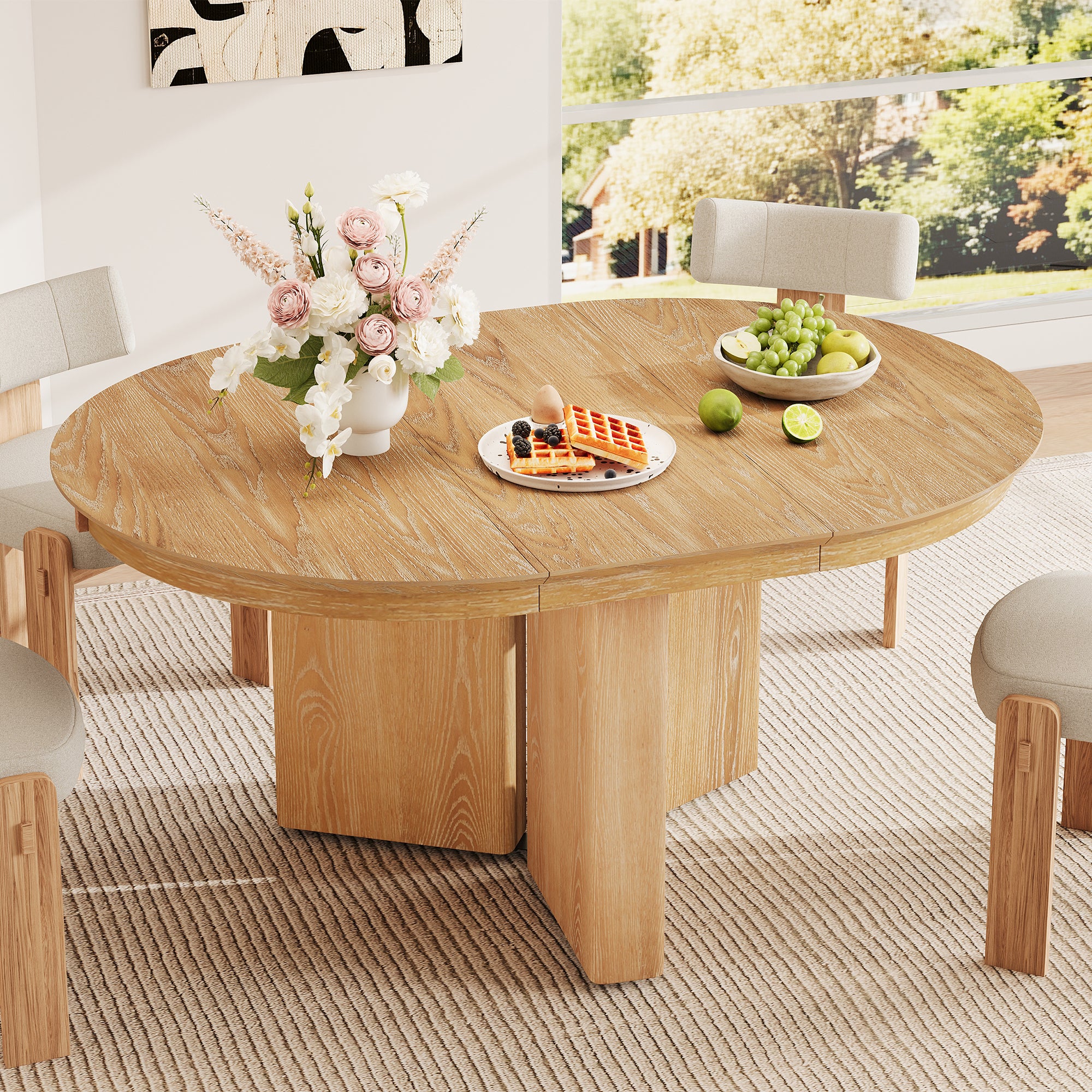 Round natural oak farmhouse table with flowers and cream chairs by a window