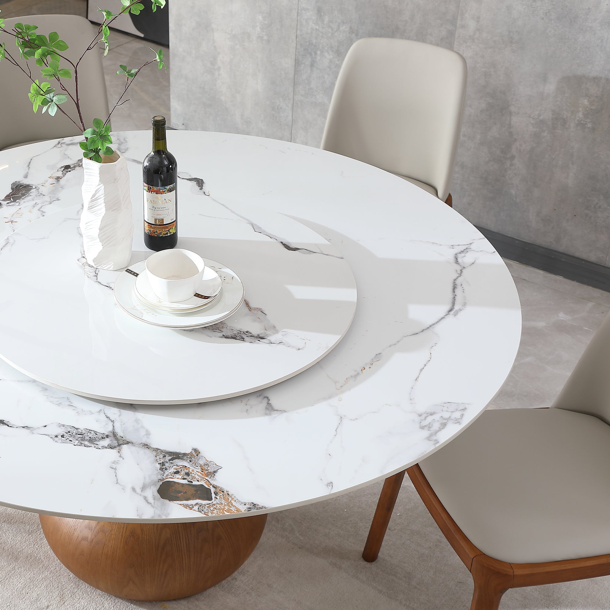 Overhead close-up of the marble-look tabletop and turntable with a wine bottle, vase and cup