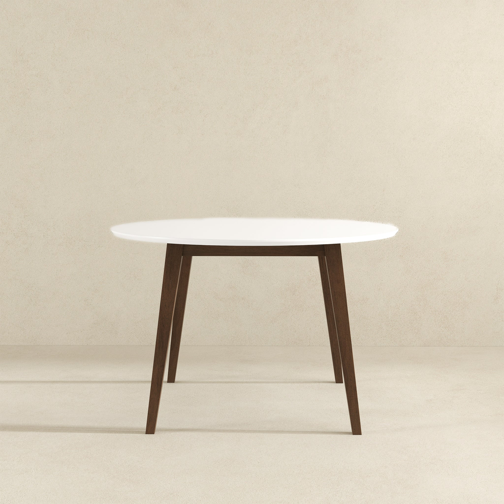 White round dining table with walnut legs, front view on beige studio background