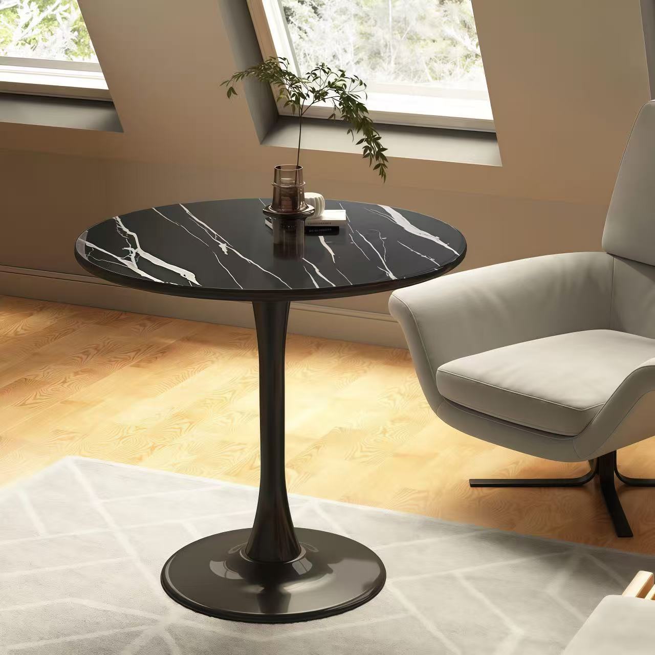 Three-quarter view of black marble bistro table by an accent chair in a bright nook