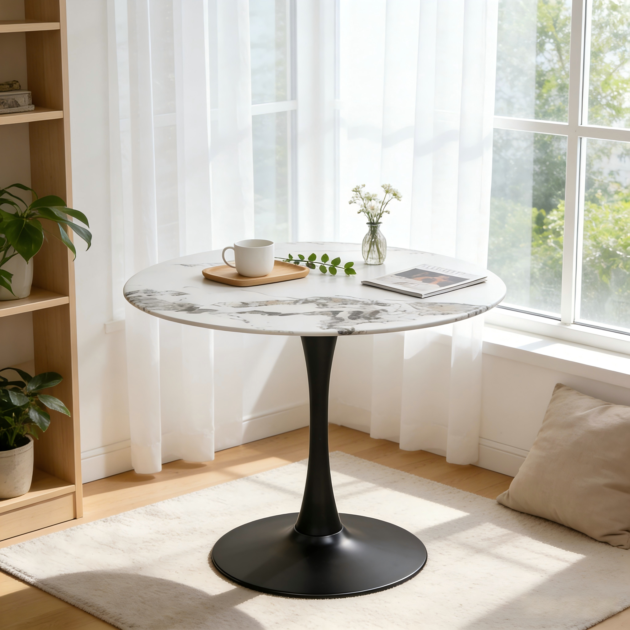 Faux marble tulip dining table with black pedestal styled with a cup and flowers by a window