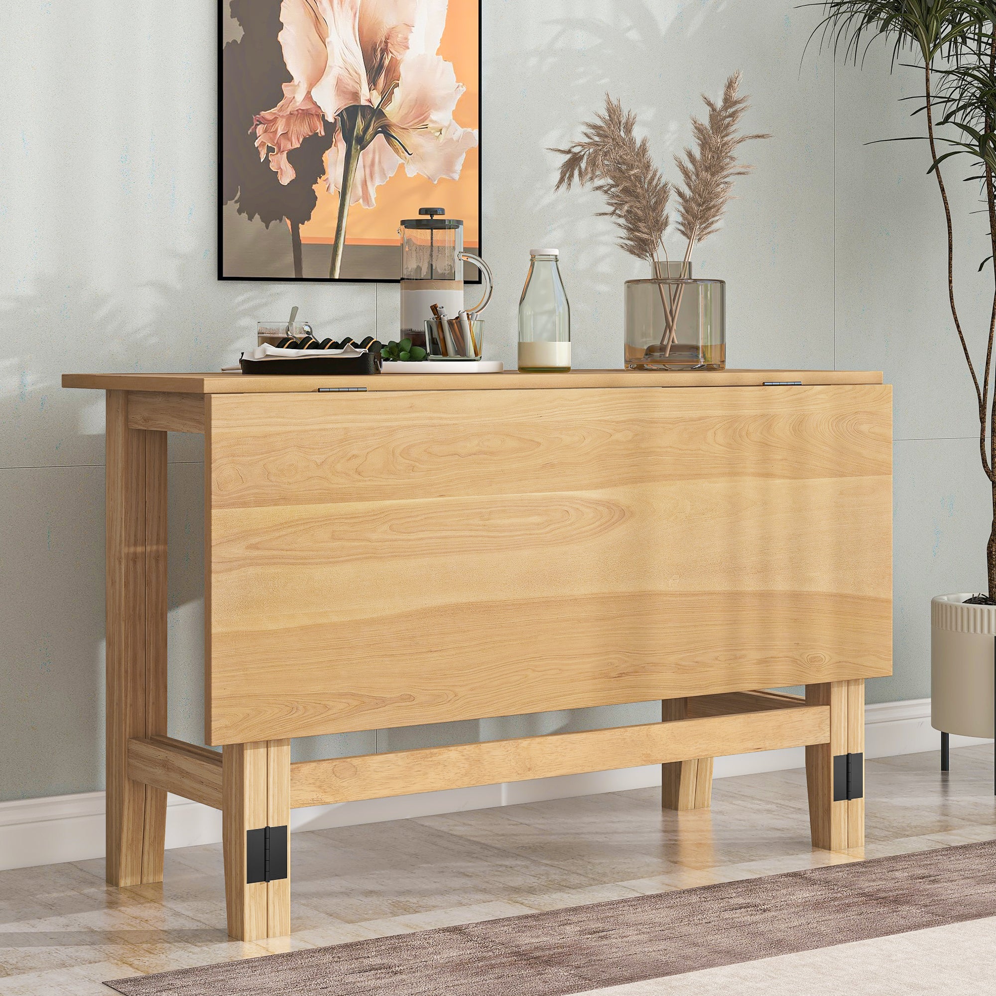 Natural wood farmhouse drop-leaf dining table folded as a console against a wall with coffee accessories