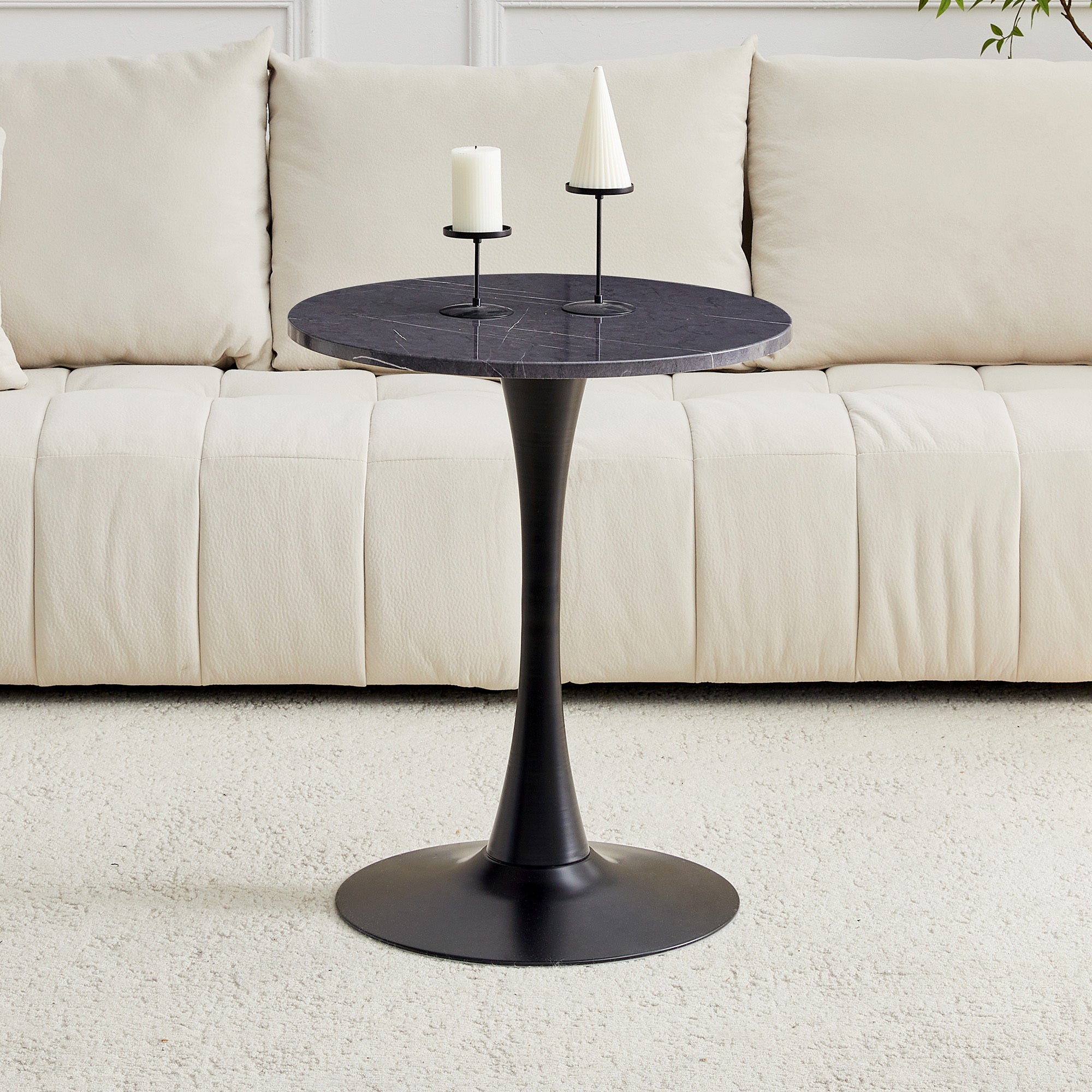 Black faux marble bistro table with a pillar candle and cone candle beside cushions, three-quarter view