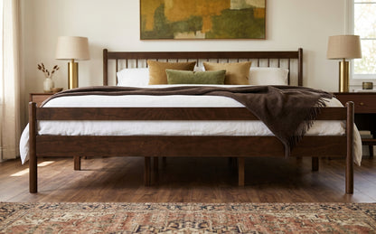 Wide shot of walnut king bed framed by bedside lamps