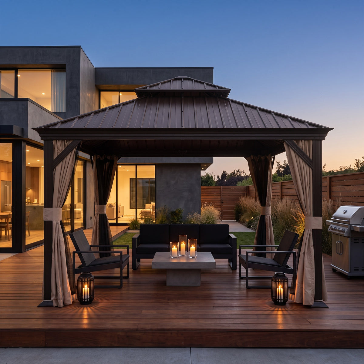 Brown 12x12 hardtop gazebo with tied back curtains over a sofa and candlelit table on a wood deck at dusk