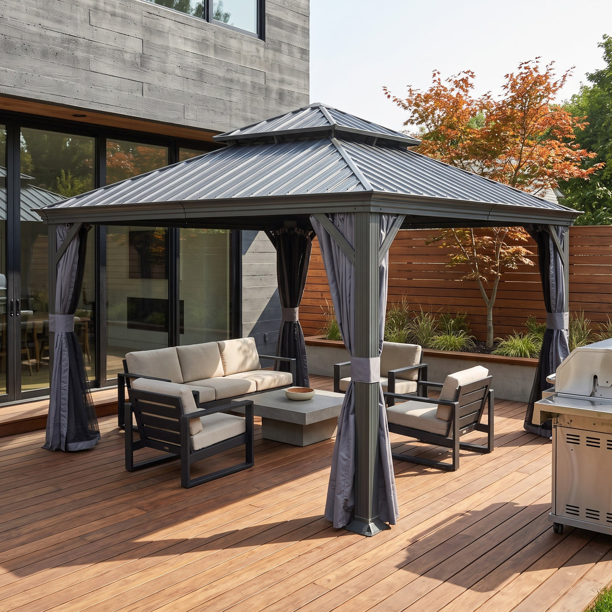 Gray 12x12 hardtop gazebo with tied back curtains over a sofa and lounge chairs on a wood deck