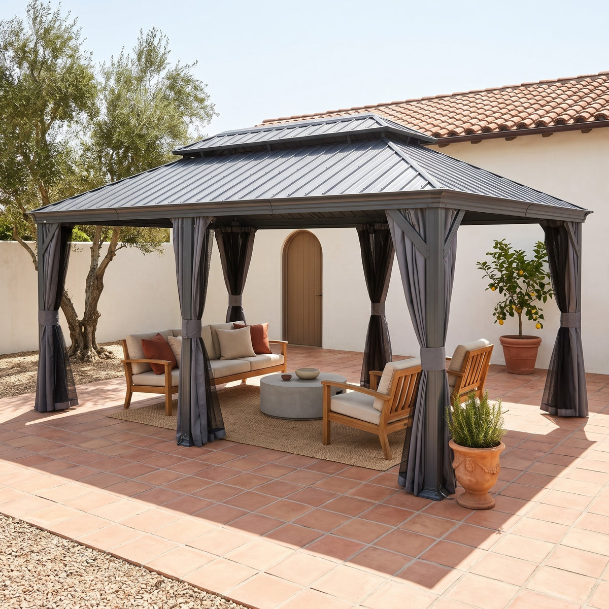 Gray aluminum 12x18 double roof hardtop gazebo with tied back curtains over a teak sofa set on a terracotta patio