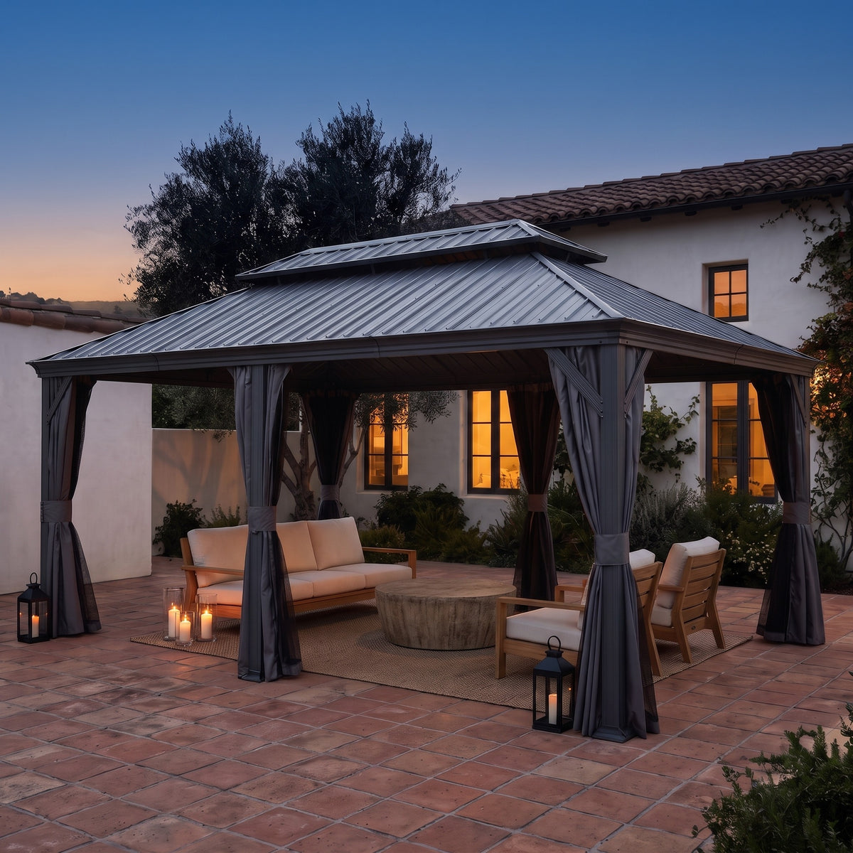 Gray aluminum 12x18 double roof hardtop gazebo with tied back curtains over a lounge set on a tile patio at dusk