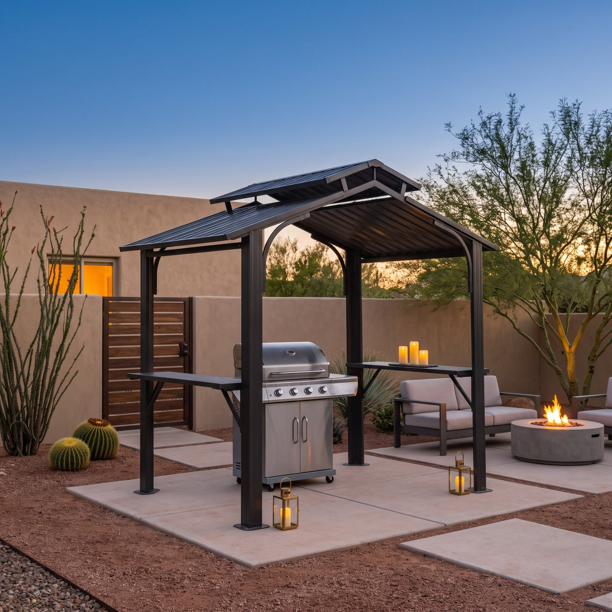 Gray metal double roof grill gazebo with side shelves over a gas grill on a desert patio at dusk