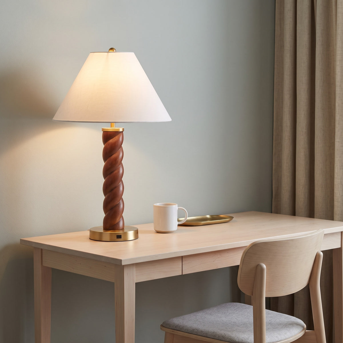 Table lamp with twisted wood-look column, brass base and white shade, lit on a maple desk