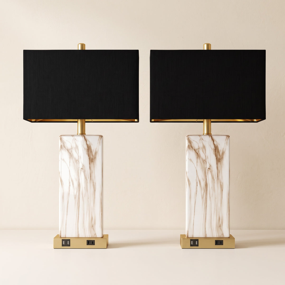 Pair of white marble-look ceramic table lamps with black rectangular shades and gold bases on an ivory backdrop