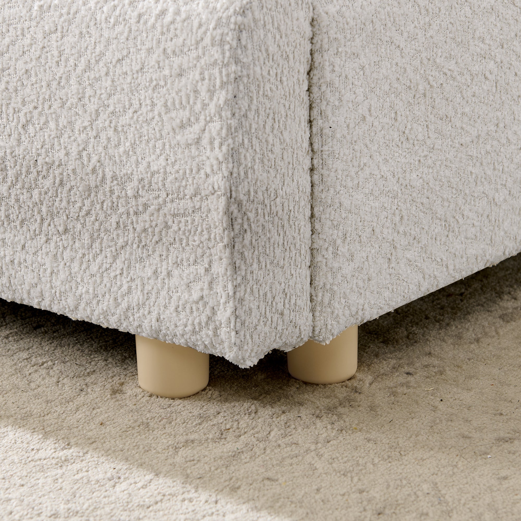 Close-up of wood leg supporting upholstered bed frame corner