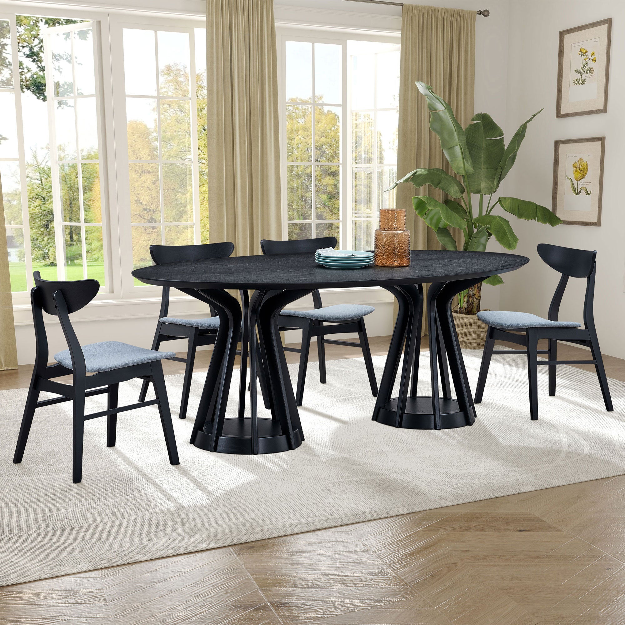 Black oval pedestal dining set with four chairs in a bright dining room