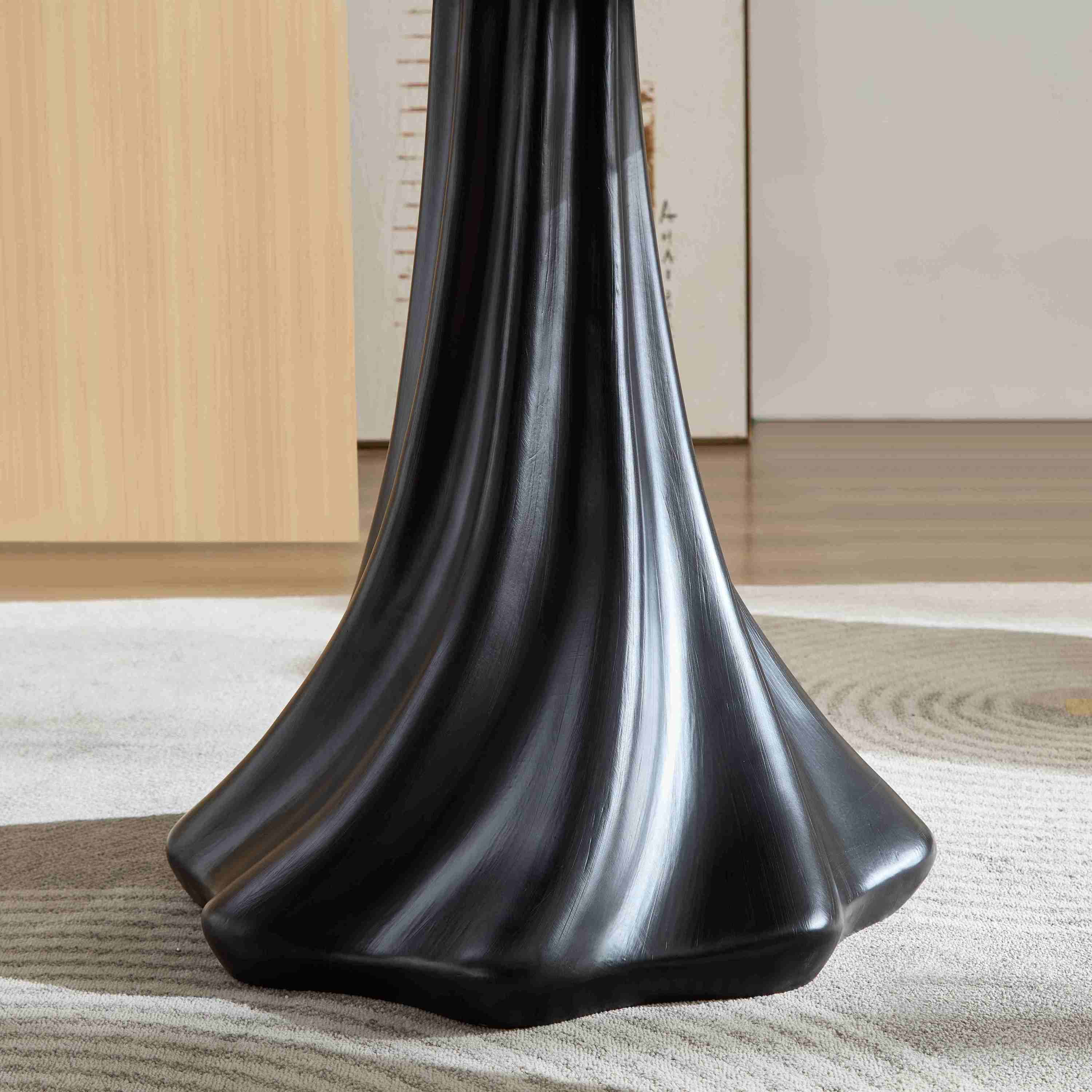 Close-up of the black fluted pedestal base of the petal dining table on a rug