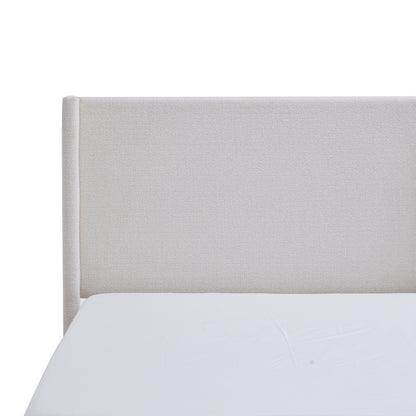 Lifestyle shot of cream wingback bed with knit throw blanket
