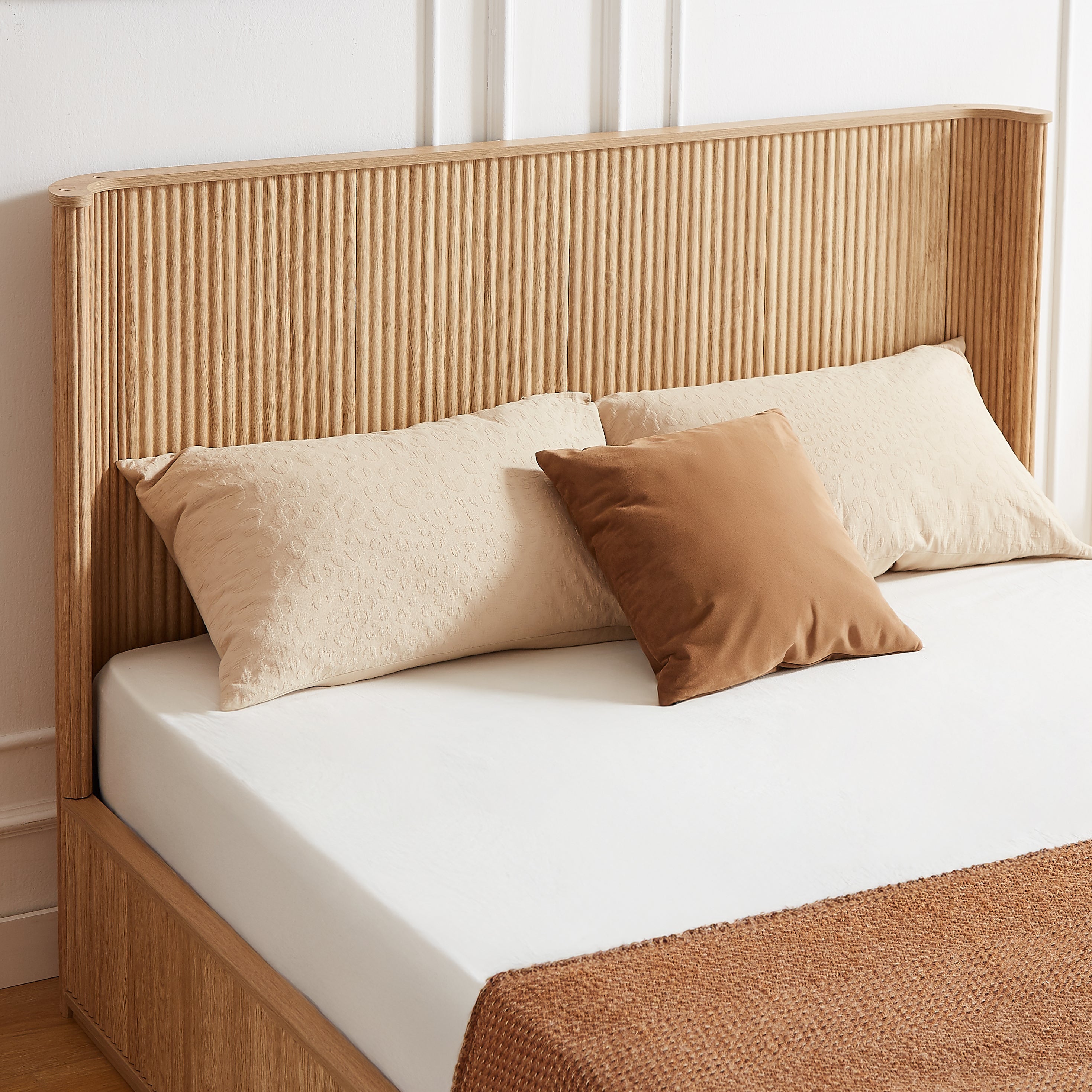 Close-up of the tall fluted natural oak headboard with beige and camel pillows #Color_Natural Oak