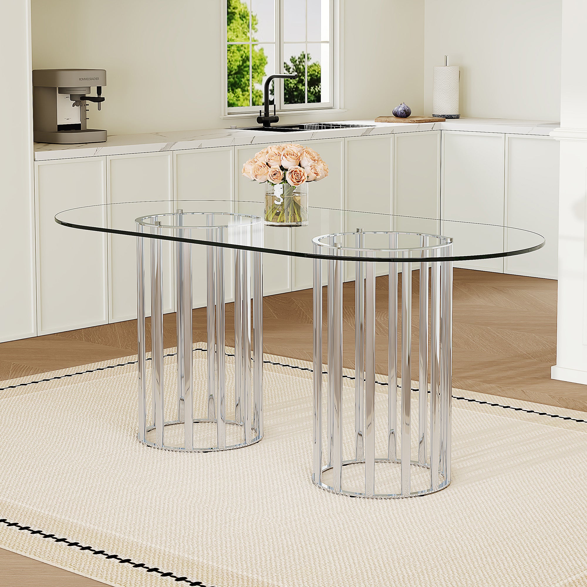Oval glass dining table with silver double-column base, styled in a white kitchen with roses on top.