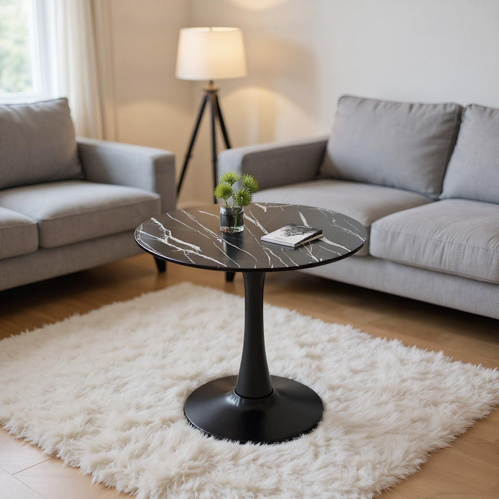 Black marble round table styled as a coffee table beside a gray sofa in a living room