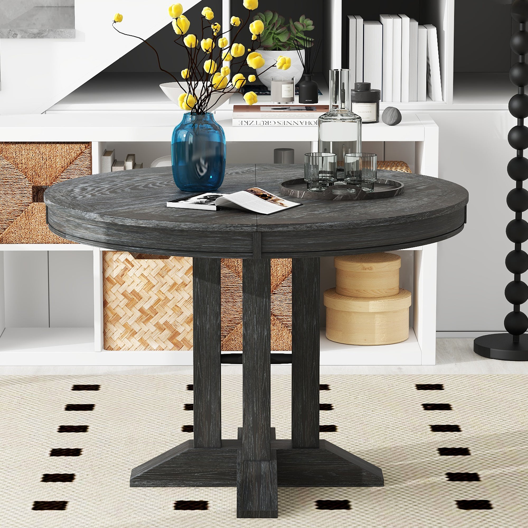 Black round dining table styled in front of white bookshelves