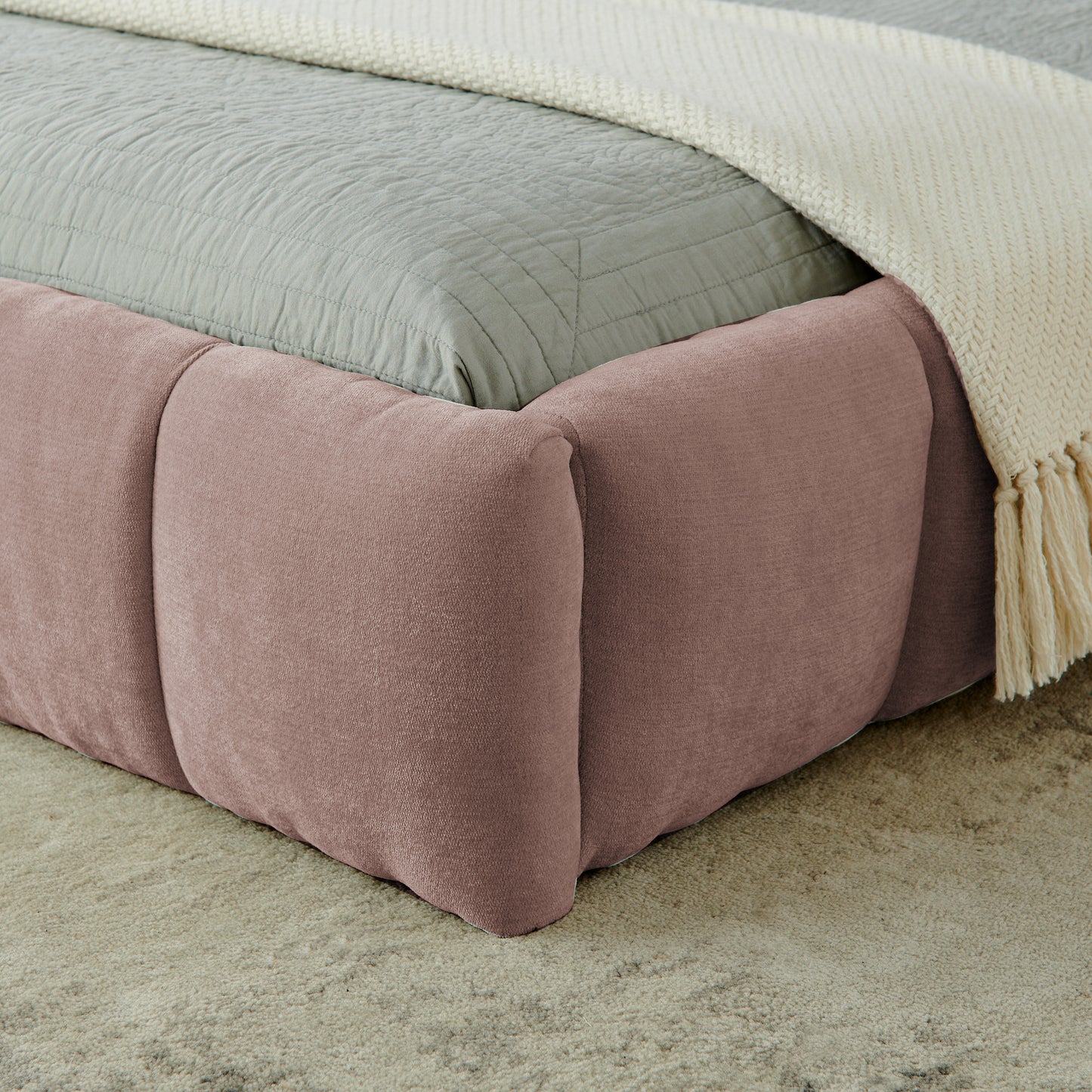 Close-up of pink chenille footboard corner with cream throw blanket