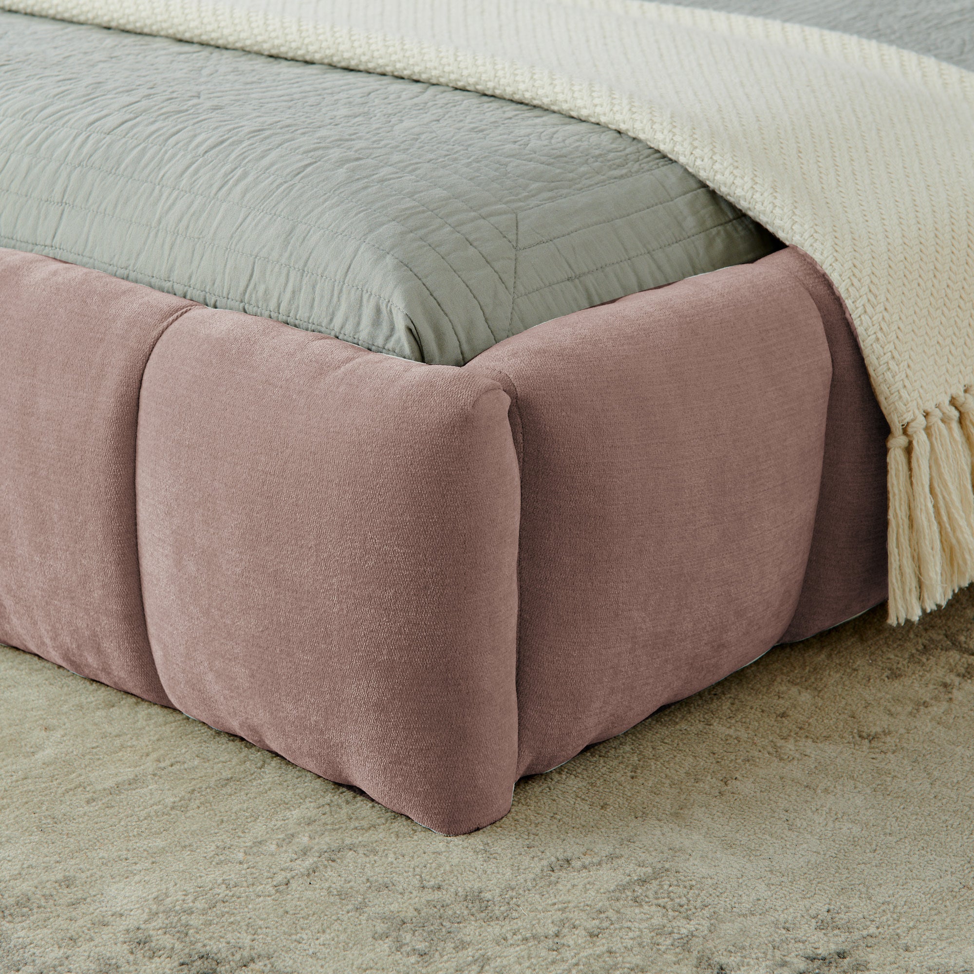 Close-up of pink chenille footboard corner with cream throw blanket