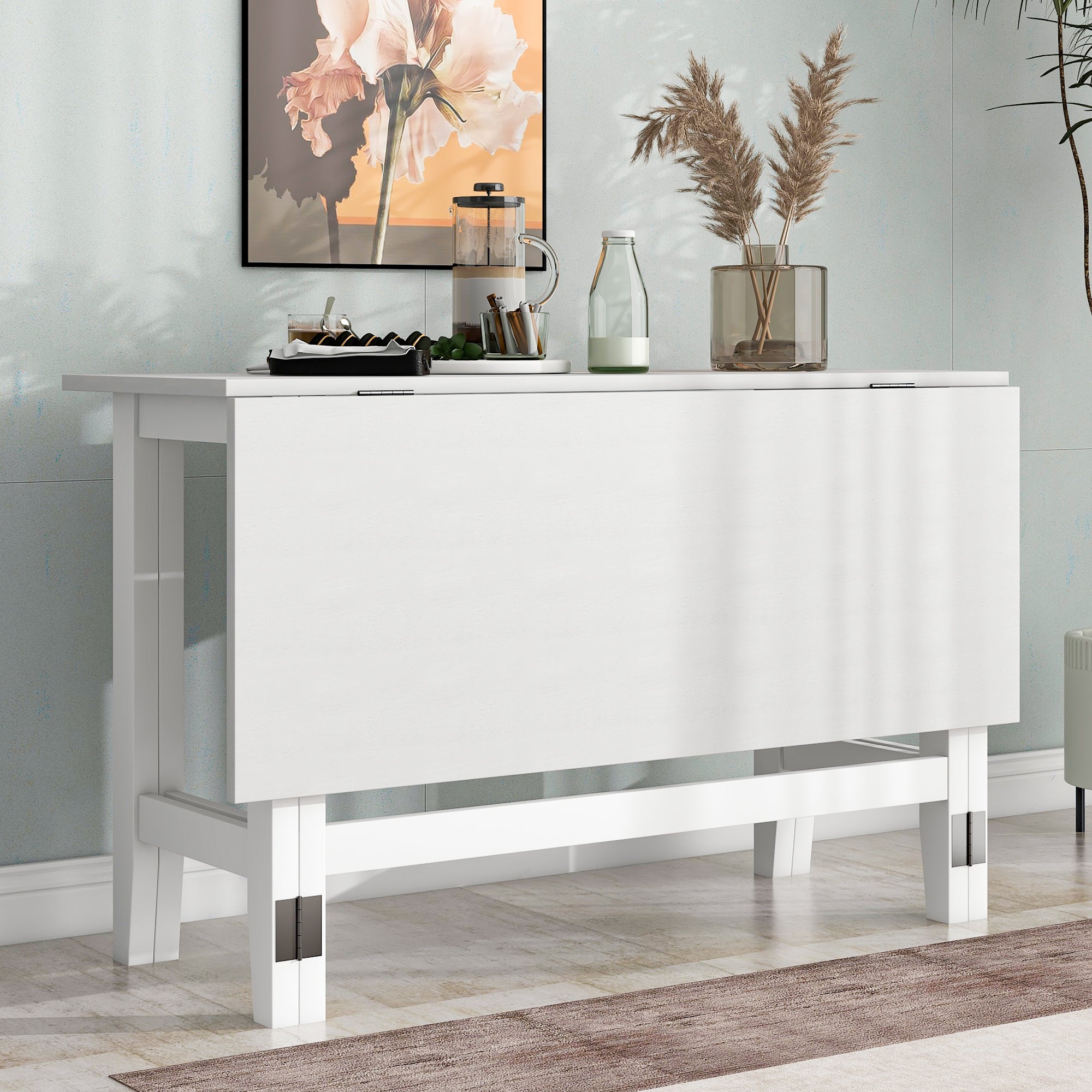 White farmhouse drop-leaf dining table folded as a narrow console against a wall with coffee accessories