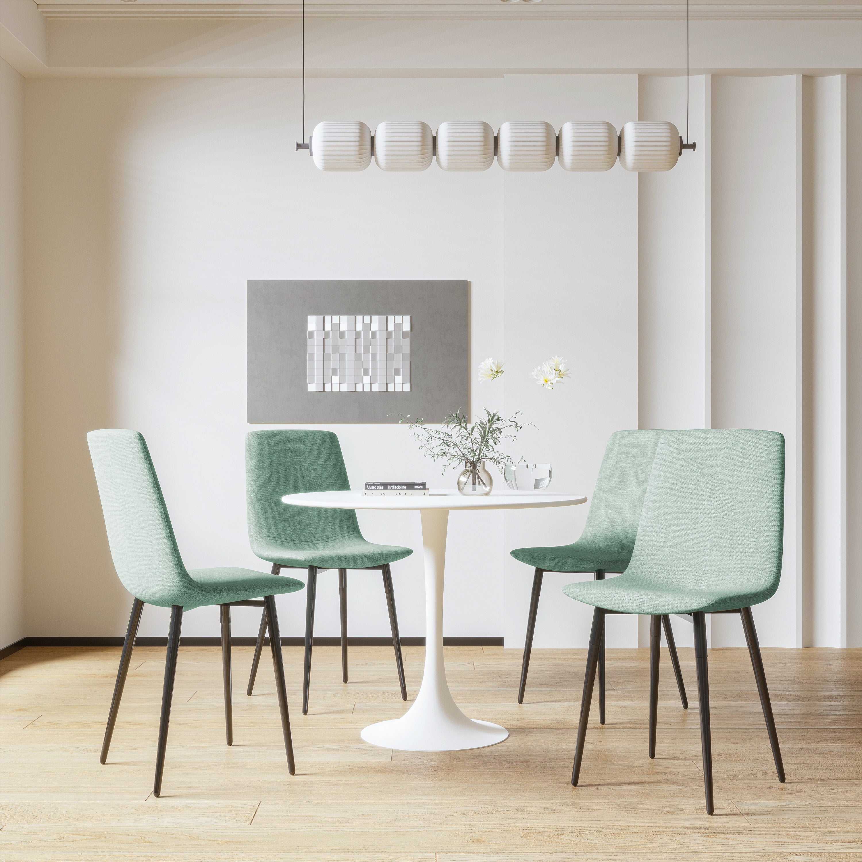 White tulip dining table with four green chairs beneath a tube pendant light
