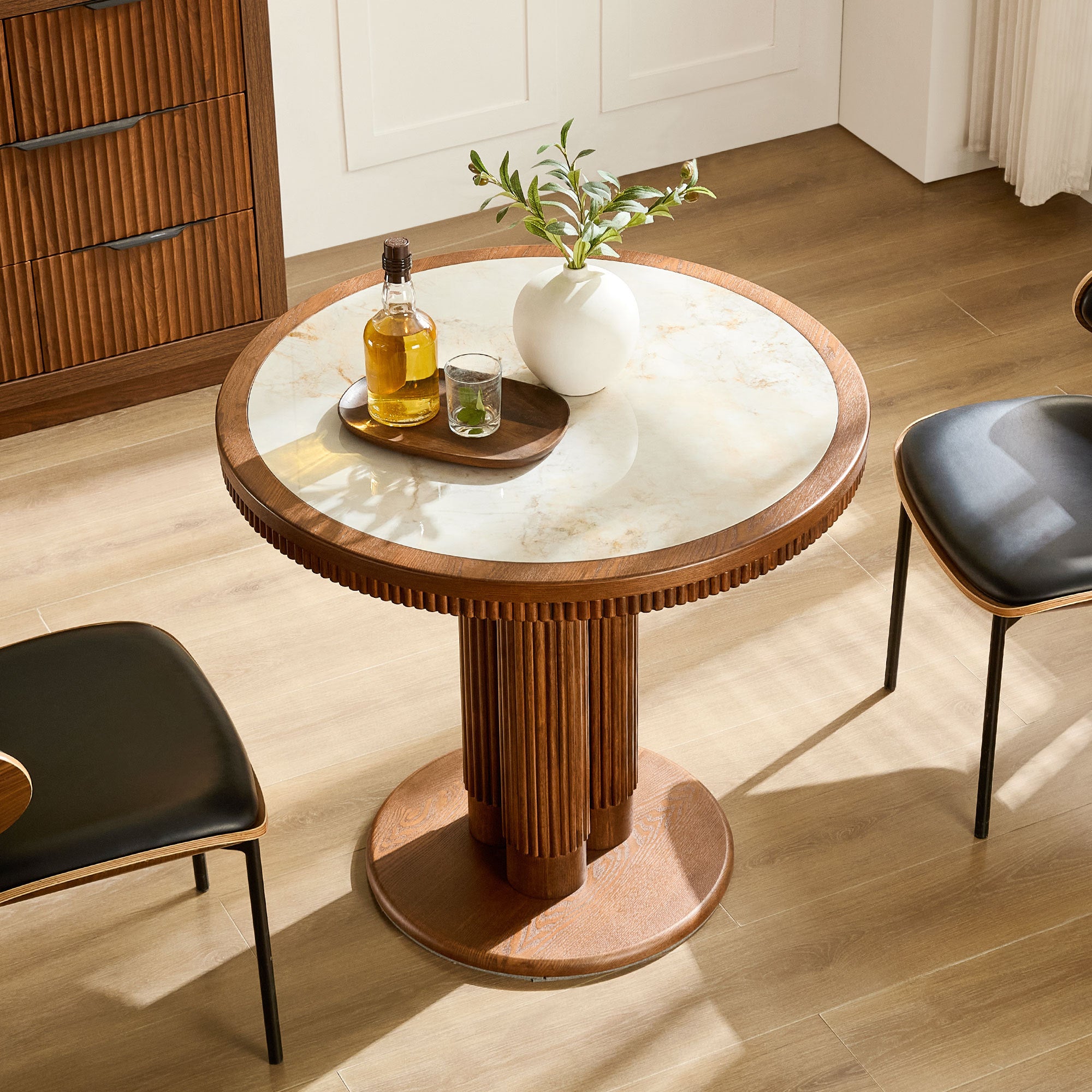 Overhead angled view of round walnut dining table with white stone top and styling decor