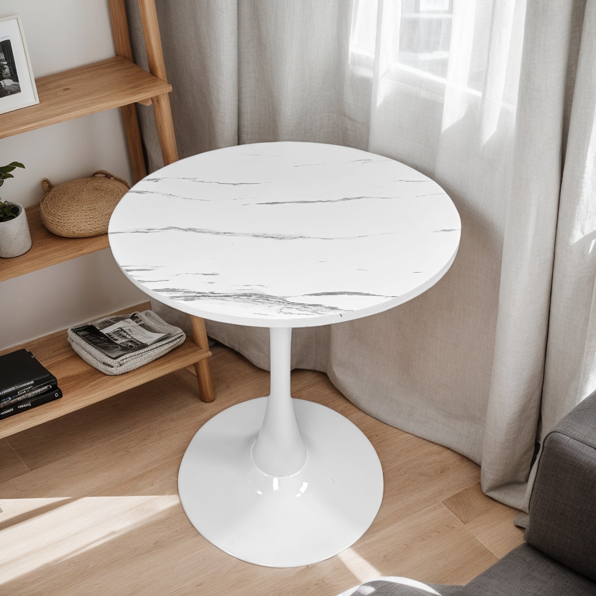 White faux marble tulip bistro table in a styled living room corner beside a wood shelf, three-quarter view