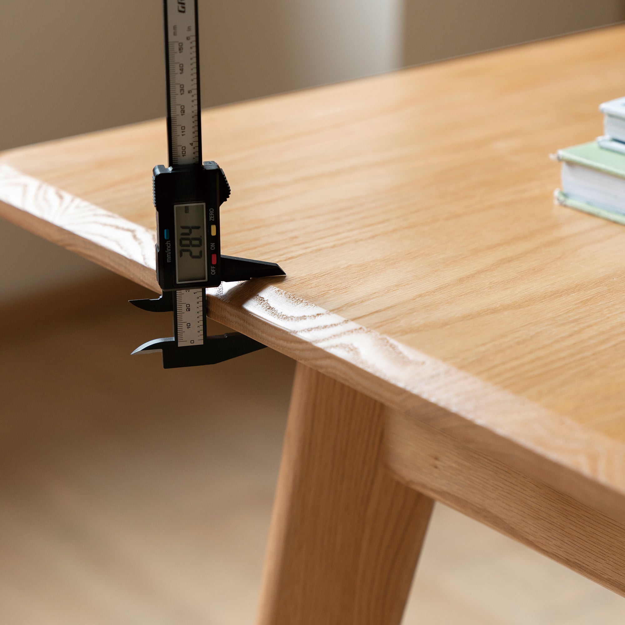 Close-up of a digital caliper measuring the oak tabletop edge thickness