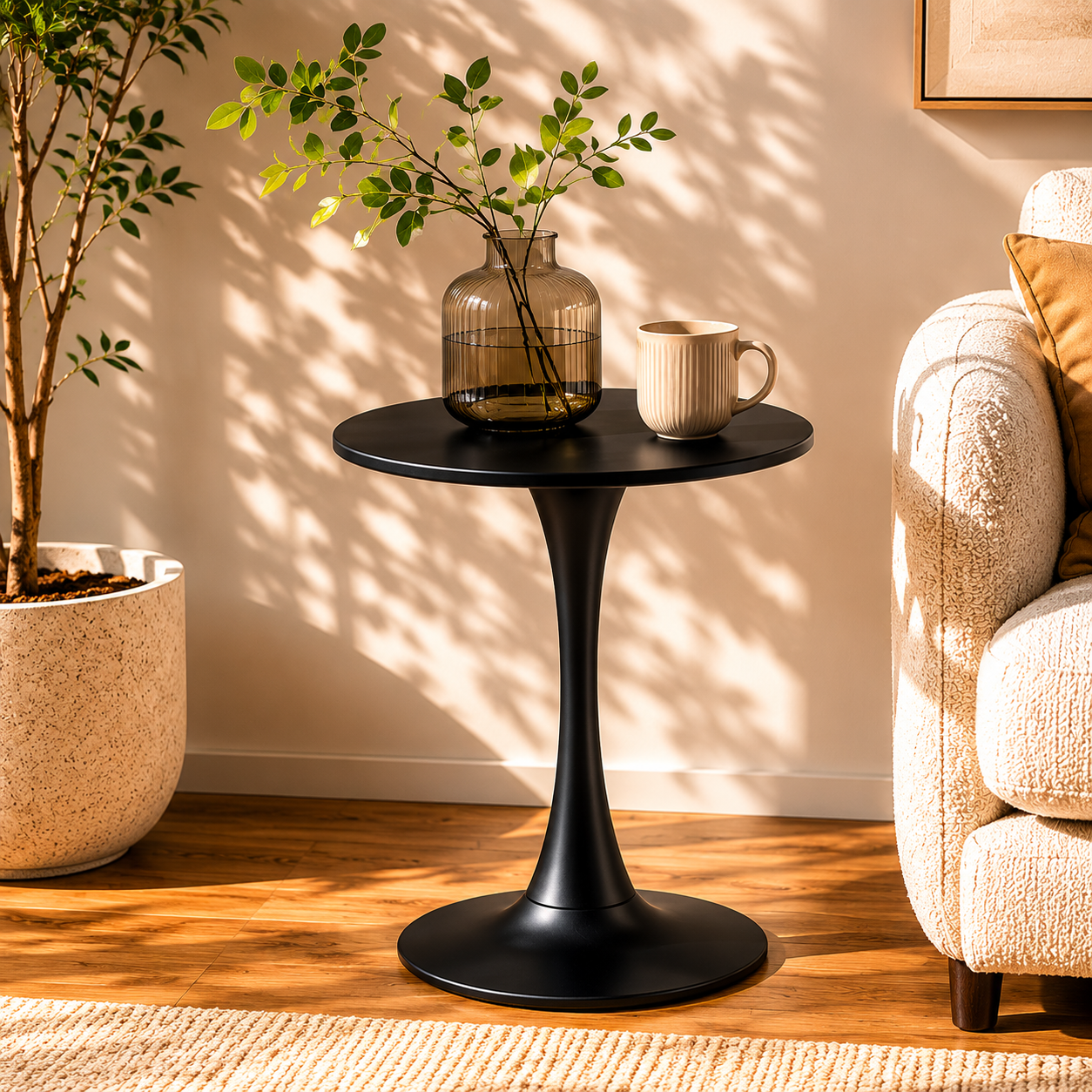 Black modern round bistro table with tulip pedestal in a sunny corner beside a cream sofa