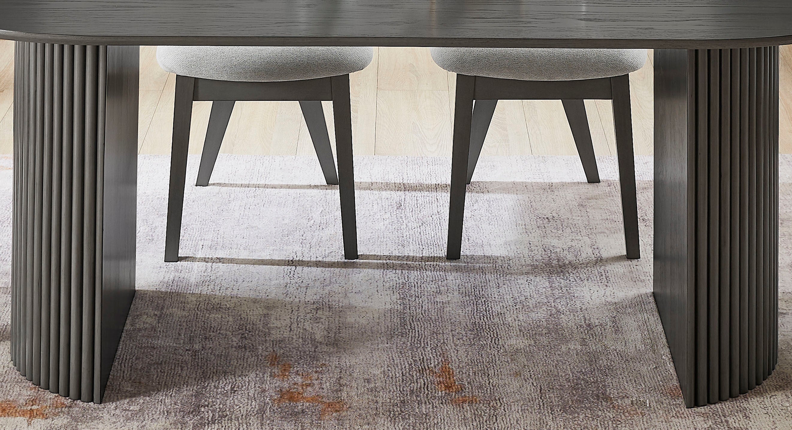 Under-table view of the gray oak oval dining table's dual pedestal bases with two chairs