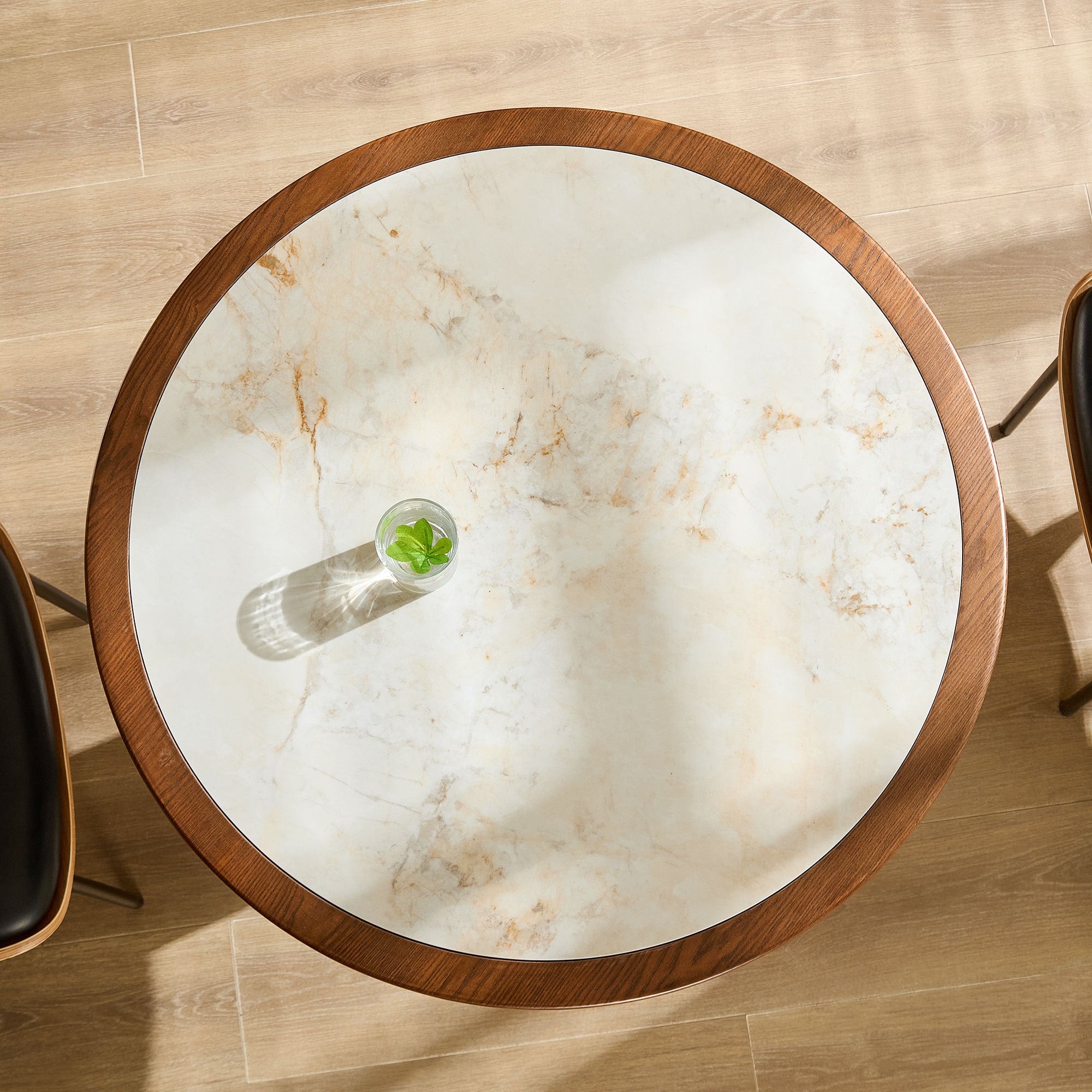 Overhead view of the round table's white sintered stone top with a water glass