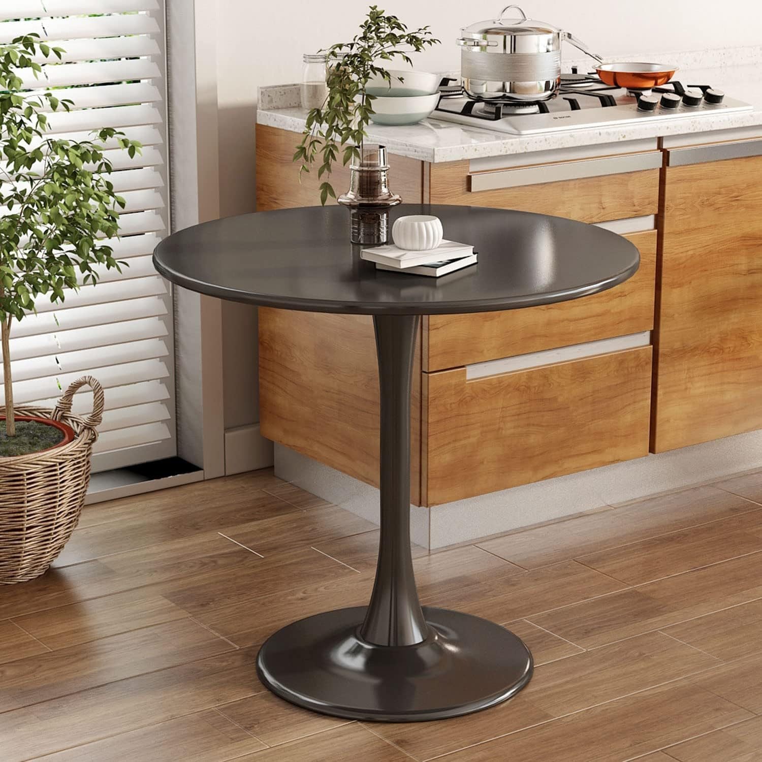 Round black tulip-base bistro table styled in a kitchen with wood cabinets and a plant