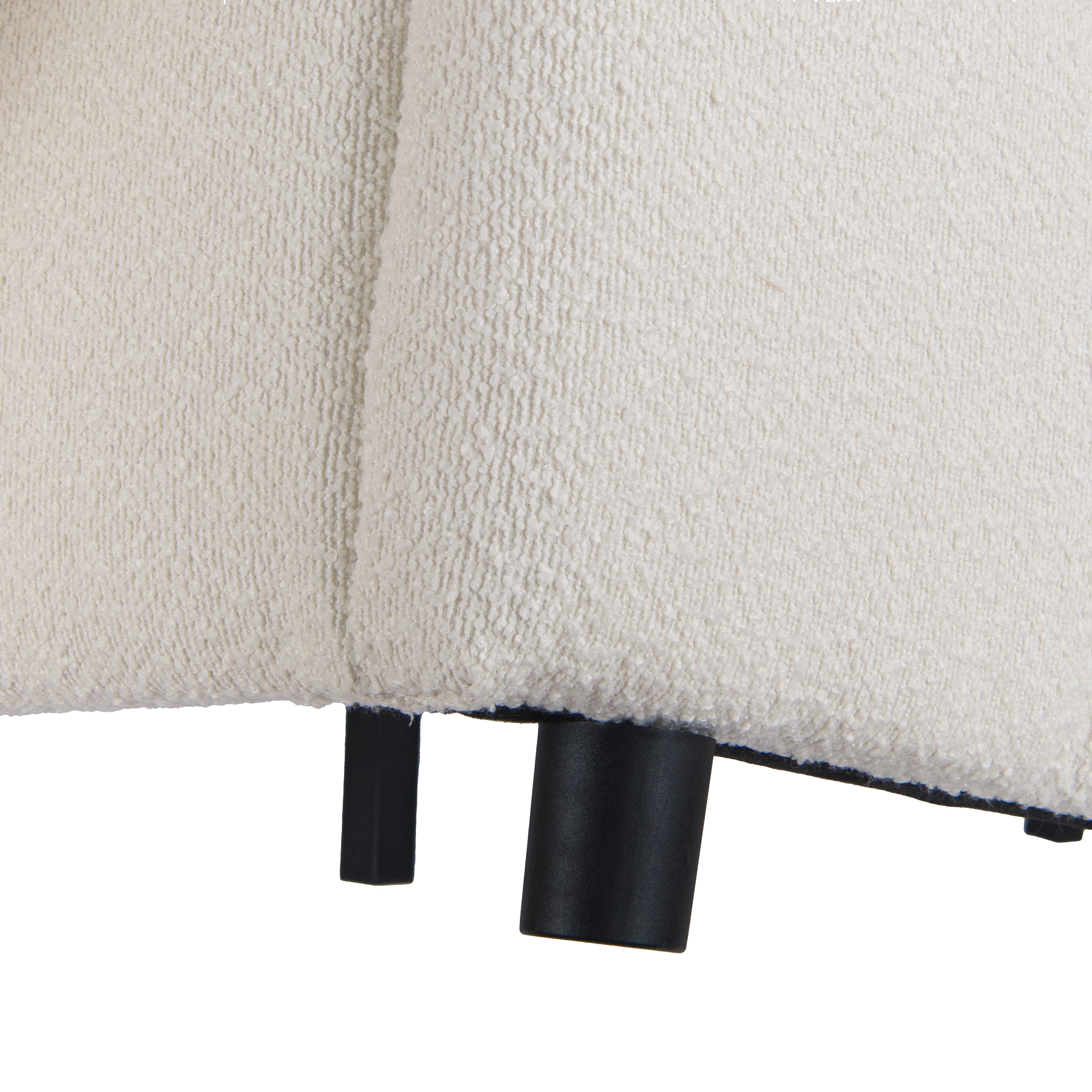 Close-up of stacked black support legs on beige bouclé platform bed