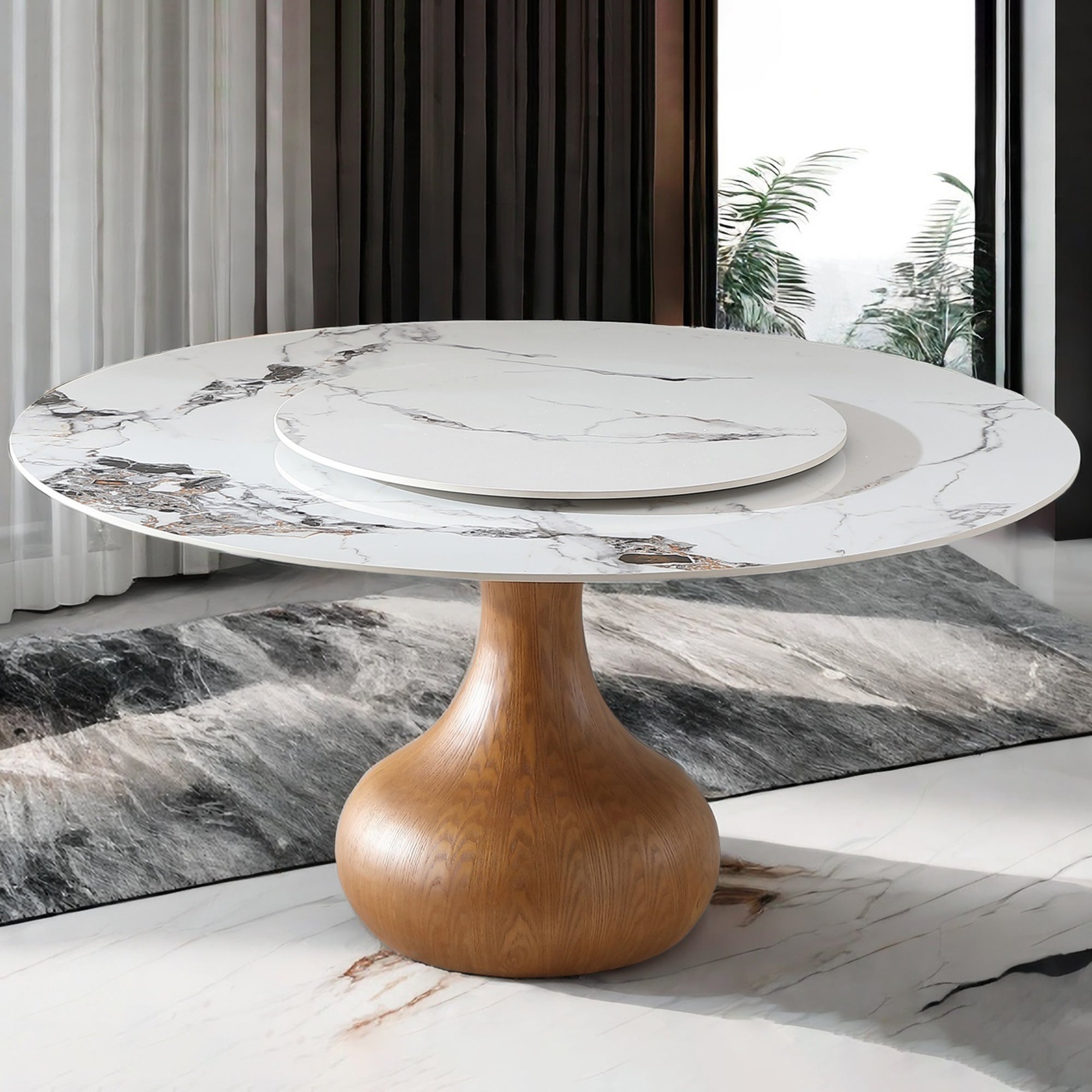 White marble-look sintered stone table with turntable styled by curtains and a plant, three-quarter view