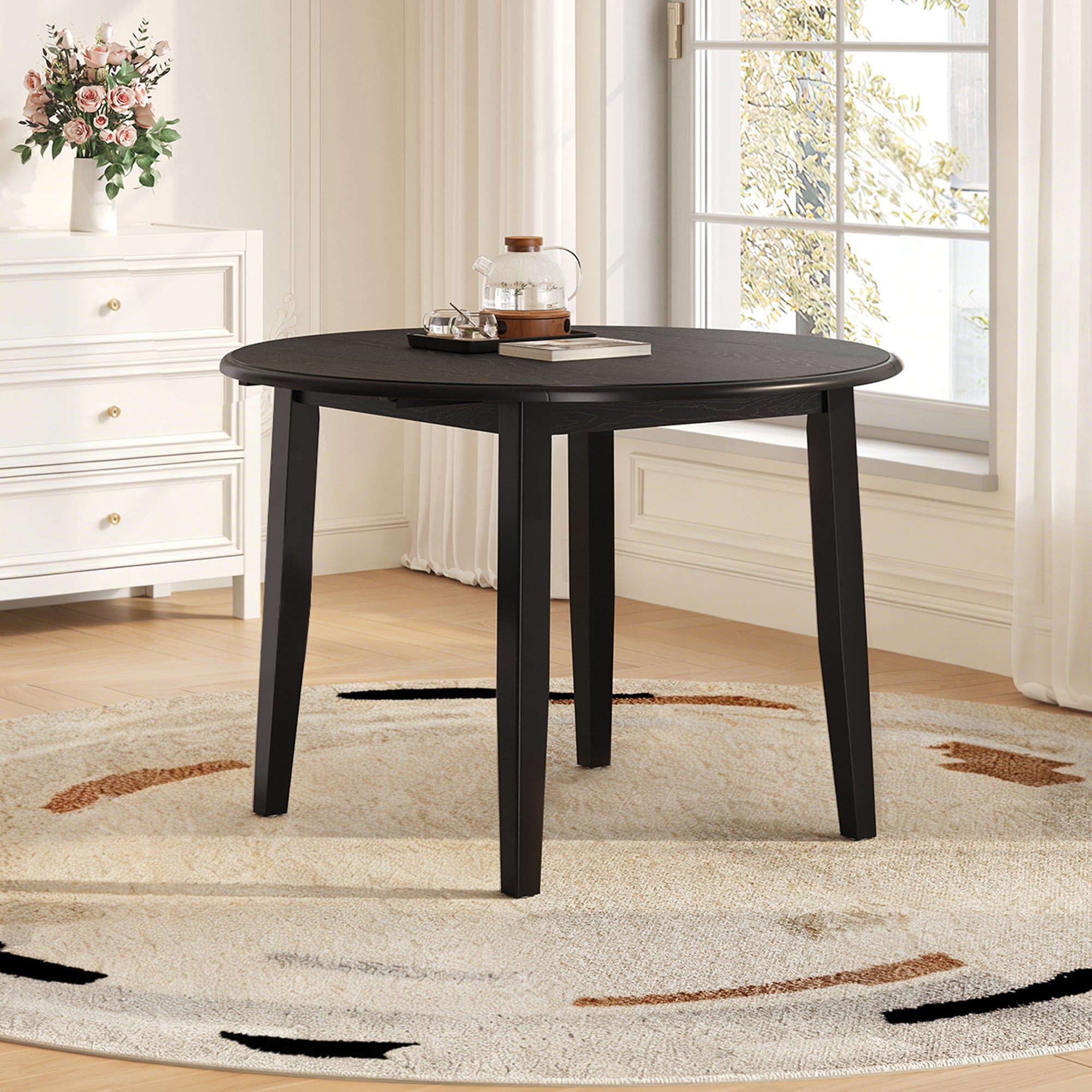 Styled room with the black round drop-leaf table set beside a window