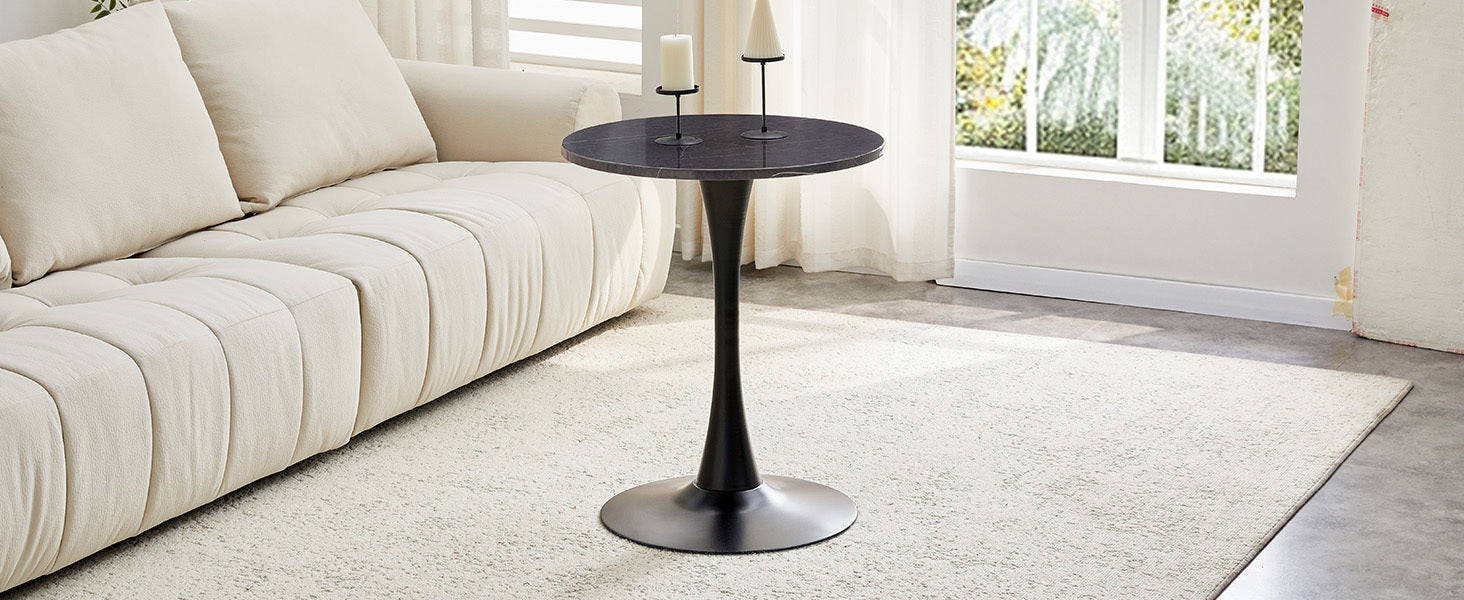 Black marble-look bistro table with candle holders beside a cream sofa in a sunlit room, three-quarter view