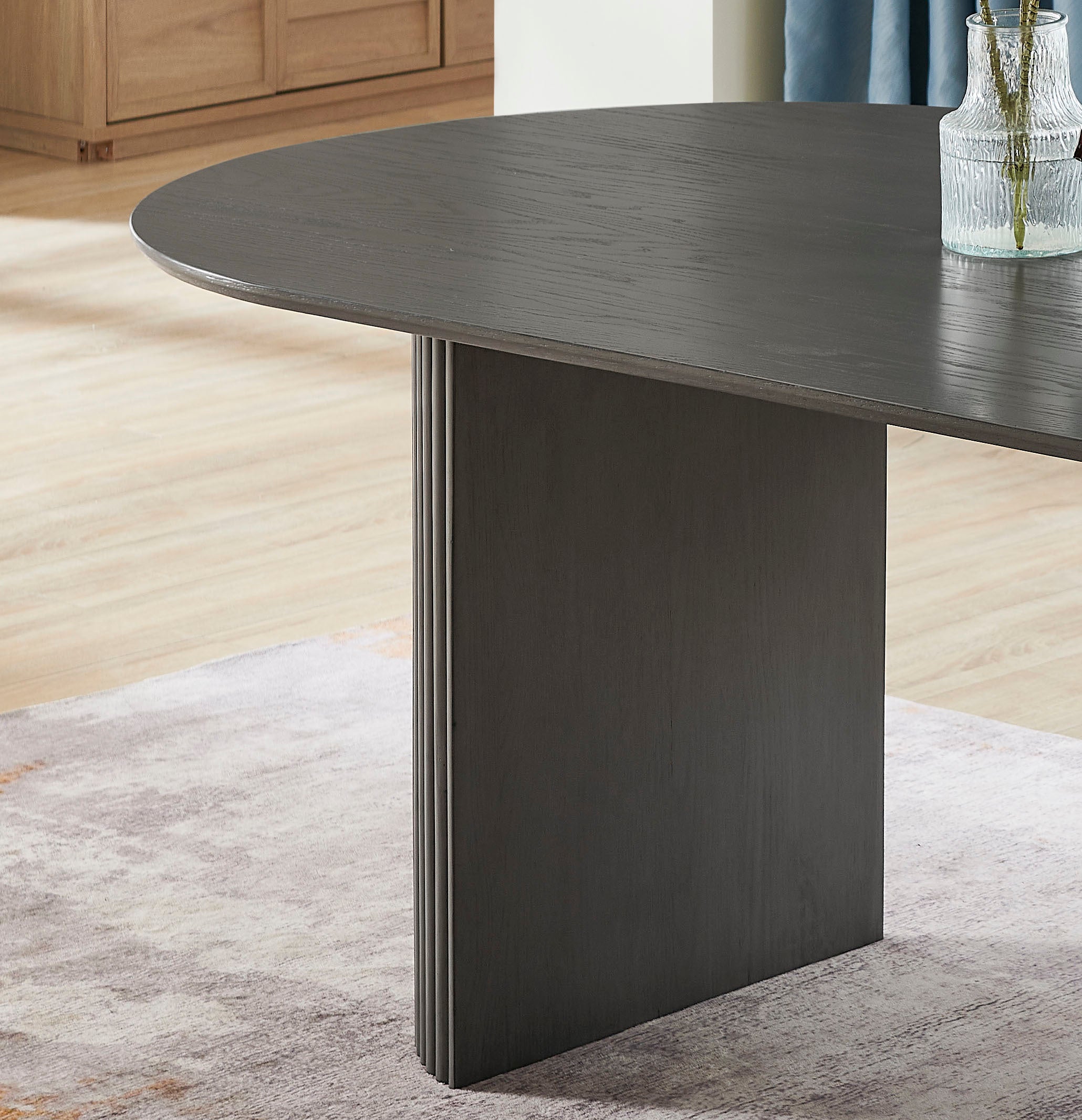 Close-up of the flat panel pedestal leg and rounded edge of the gray oak dining table