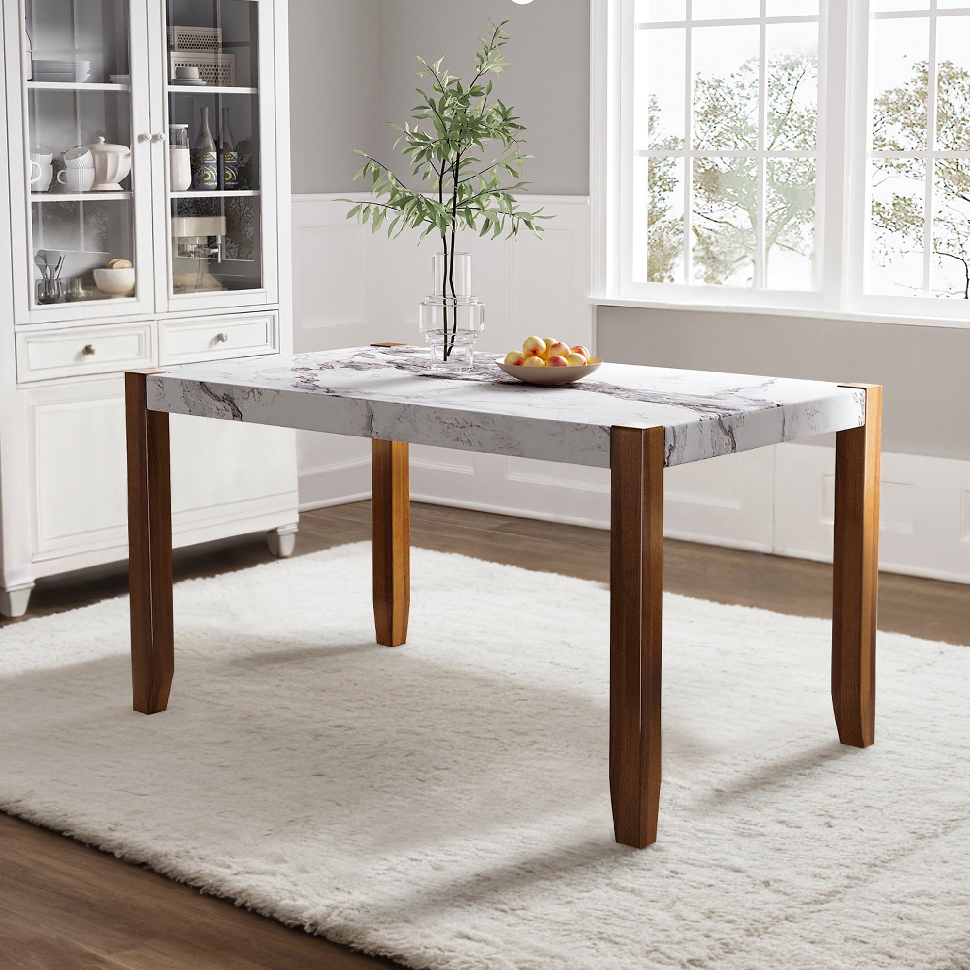 White faux marble dining table with brown wood legs styled in a bright dining room with peaches