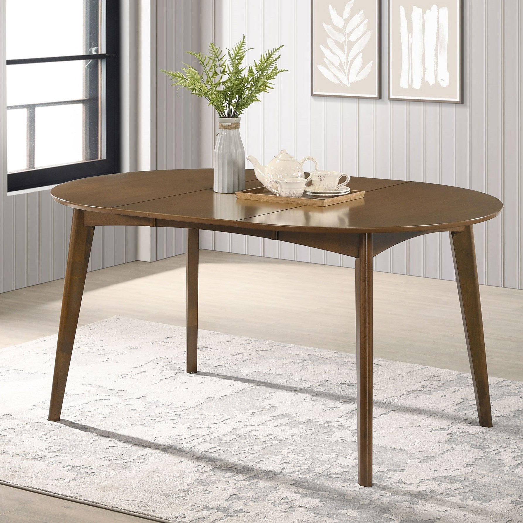Walnut oval dining table styled with a plant and tea set in a bright room