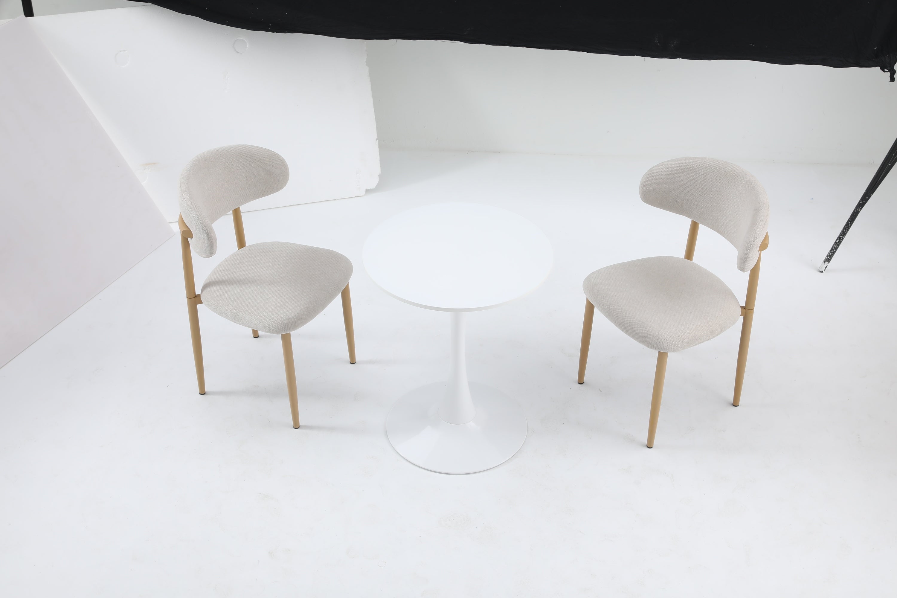 Overhead studio view of the white round bistro table with two beige upholstered chairs
