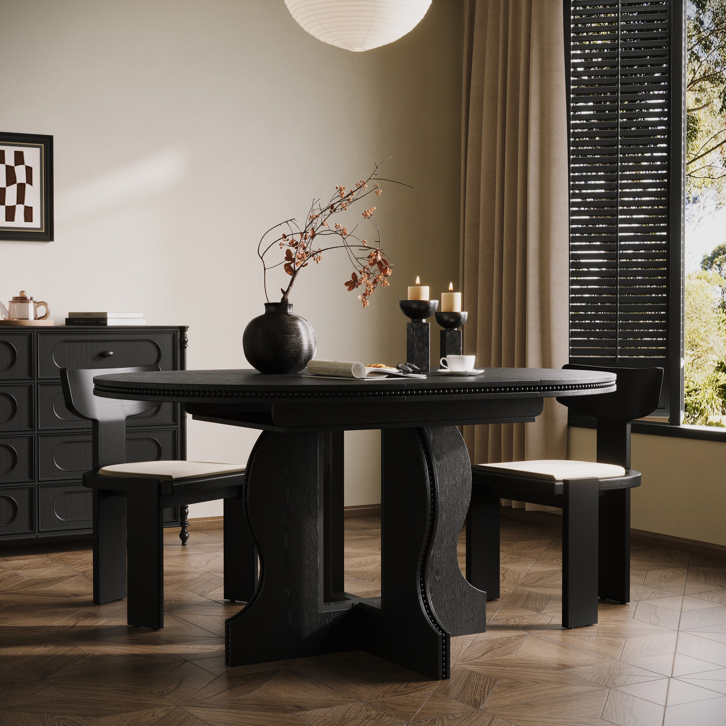 Black round pedestal dining table styled in a dining room with two chairs beside a shuttered window