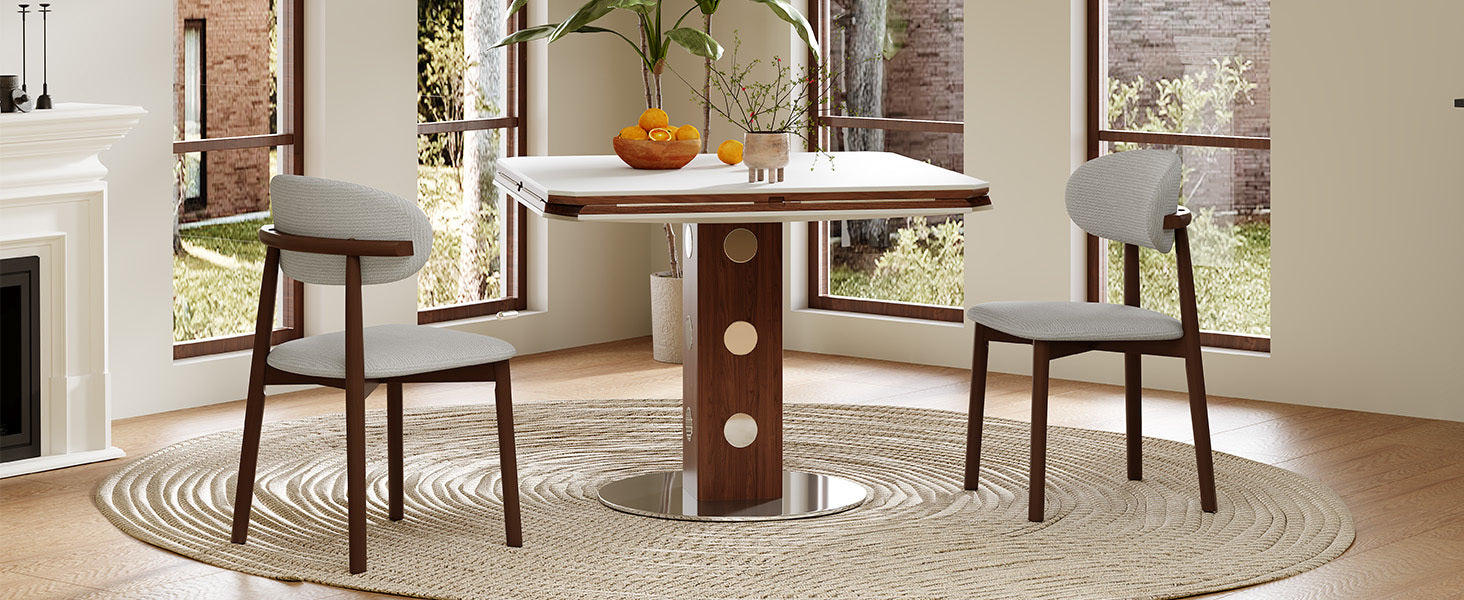 White table in square form with two gray chairs and oranges in a sunlit corner