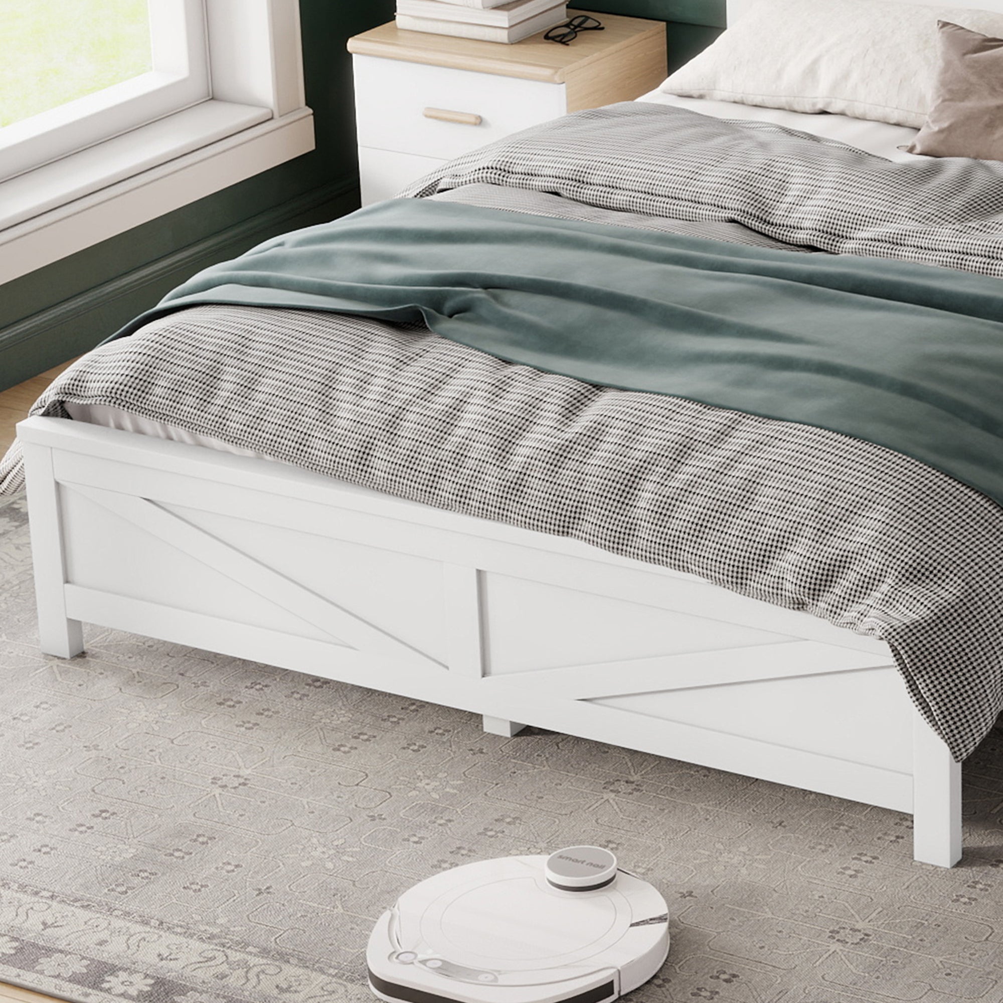 Foot of the white queen bed showing the barn door footboard panel, bedding and a robot vacuum on the rug