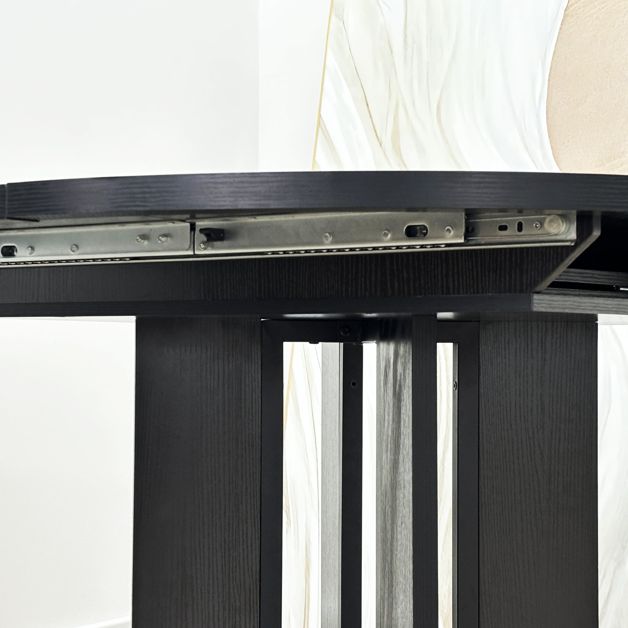Close-up of the extension slide rail mechanism beneath the black tabletop edge