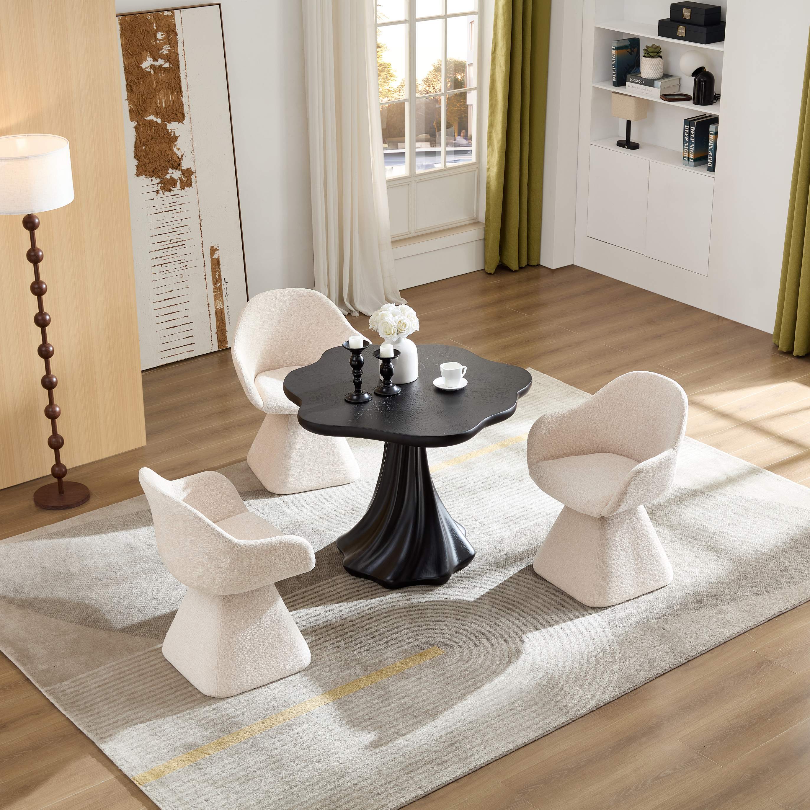Black petal dining table and three cream chairs on a rug, angled room view