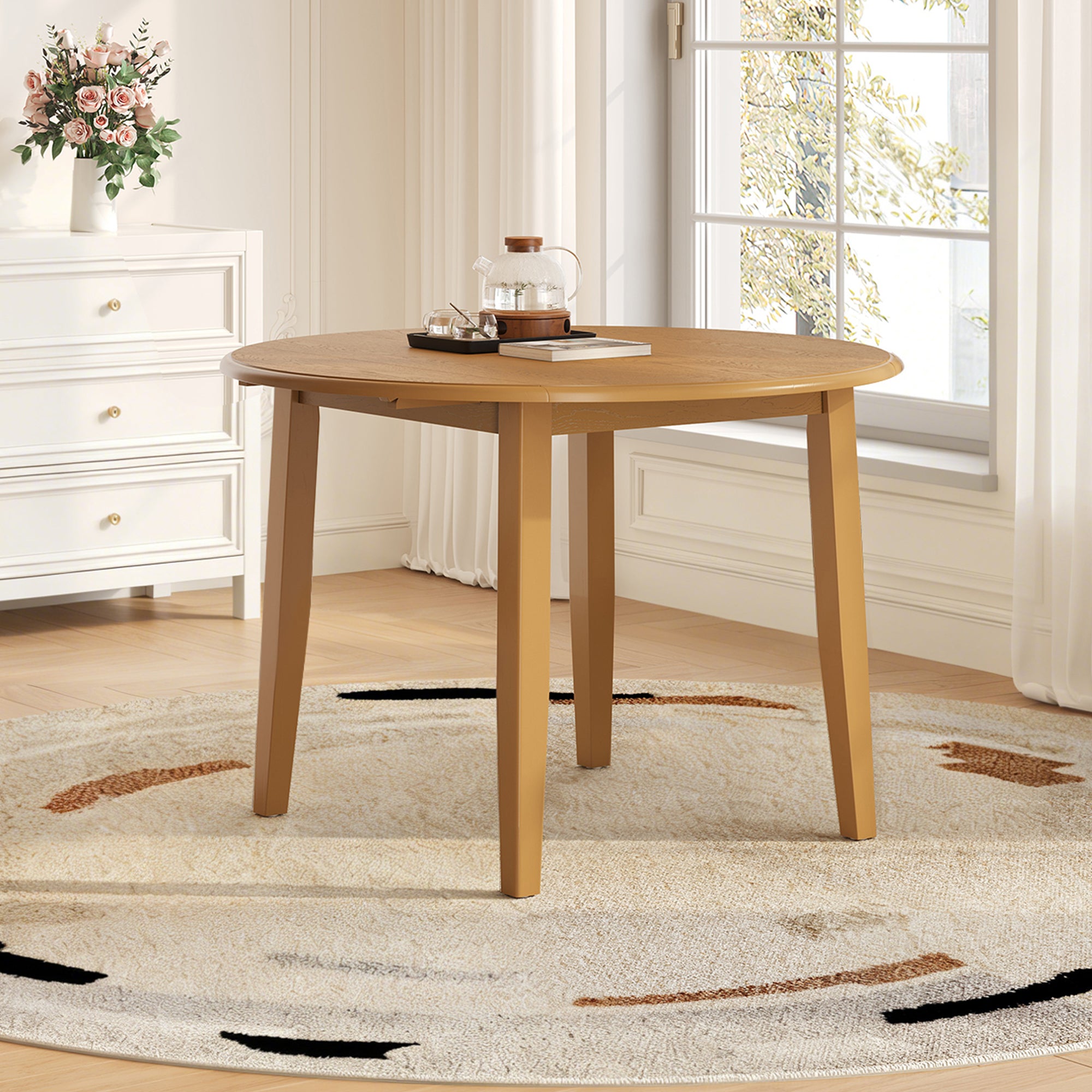 Styled room with the light brown round drop-leaf table set beside a window